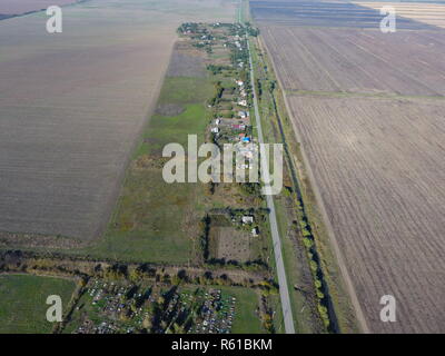 Blick von oben auf das Dorf. Man kann sehen, die Dächer der Häuser und Gärten. Straße in das Dorf. Der Blick aus der Vogelperspektive Stockfoto