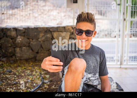 Junge hübsche Teenager boy 15 Jahre alt nehmen selfie Bild mit Handy, um das Gerät zu lächeln - social media Leben für Einfluss und Blogger - Stockfoto