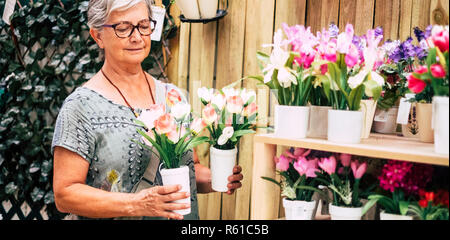 Wunderschöne reife Frau, 70 Jahre alt im Garten Shop auswählen, welche Blume Pflanze ant mit nach Hause nehmen zu kaufen Haus mehr Schönheit zu machen - Farben und Happy peo Stockfoto