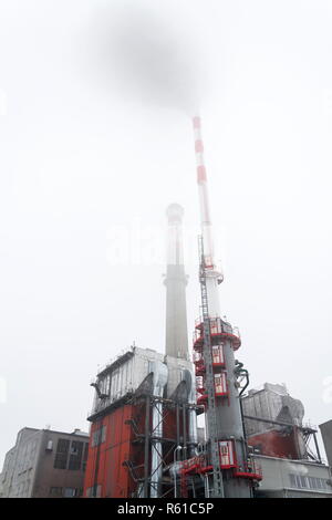 Alten eine neue Schornsteine am Heizwerk in Nebel, trüben Wintertag, Low Angle View, Energie, Klimawandel und globale Erwärmung Konzept Stockfoto