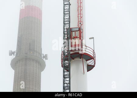 Alten eine neue Schornsteine am Heizwerk in Nebel, trüben Wintertag, Low Angle View, Energie, Klimawandel und globale Erwärmung Konzept Stockfoto