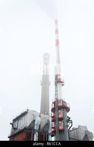 Alten eine neue Schornsteine am Heizwerk in Nebel, trüben Wintertag, Low Angle View, Energie, Klimawandel und globale Erwärmung Konzept Stockfoto