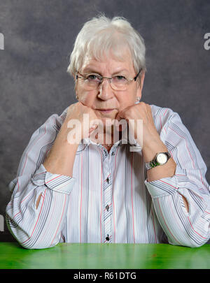 Grau behaarte ältere Frau mit Brille suchen ernsthafte Stockfoto