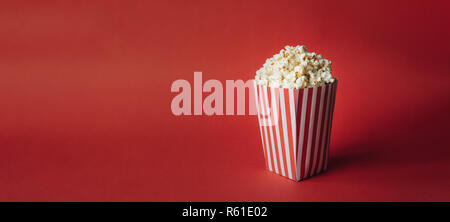 Gestreifte Box mit Popcorn auf rotem Hintergrund. Wide Format, Banner Stockfoto