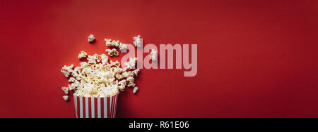 Gestreifte Box mit Popcorn auf rotem Hintergrund. Wide Format, Banner Stockfoto