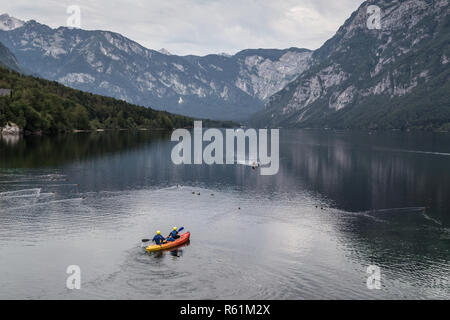 Menschen Rudern im Kanu auf ruhigen bewölkten Morgen am Bohinjer See, Alpen, Slowenien. Stockfoto