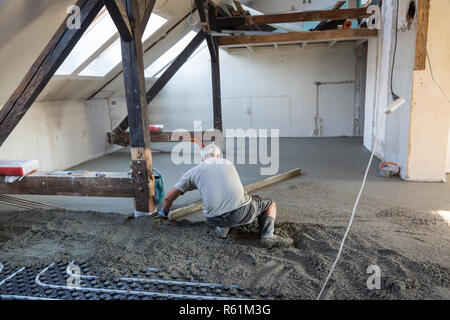 Arbeiter Nivellierung Sand und Zement Estrich auf Fußbodenheizung. Stockfoto