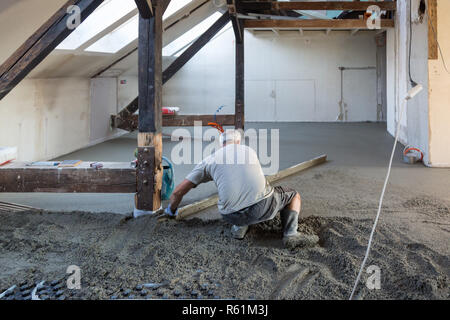 Arbeiter Nivellierung Sand und Zement Estrich auf Fußbodenheizung. Stockfoto