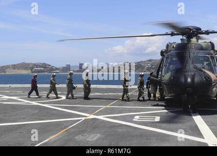 PORT Moresby, Papua Neu Guinea (Nov. 16, 2018) Mitglieder des amphibious Transport dock Schiff USS Green Bay LPD (20) eine der Royal Australian Navy helicopter zugeordnet HMAS Adelaide (L01) auf dem Flugdeck begeben. Green Bay in Port Moresby mit Sicherheit Bemühungen im Vorfeld der Asia-Pacific Economic Cooperation (APEC) Konferenz zu unterstützen und ist die zweite US-Schiff nach Port Moresby in den letzten zwei Monate besuchen. Green Bay ist Teil der Amphibischen Squadron 11 und arbeitet in der Region Interoperabilität mit Partnern zu verbessern und dienen als ready-Response Force für jede Art von Kontingenz. Stockfoto