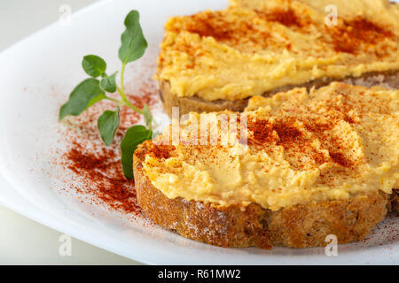 Zwei Sandwiches mit Hummus und Paprikapulver auf einer weißen Platte Stockfoto