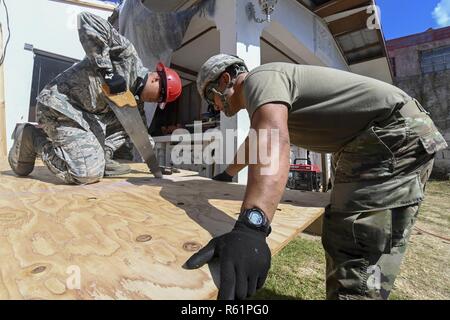 Us Air Force Staff Sgt. Francis Flores, 254Th rasch verlegbare Schweren operativen Reparatur Squadron Ingenieure strukturelle Handwerker, und die Armee der Sgt. Melvin San Nicholas, 797 . Engineer Company, sah Sperrholz zu helfen ein Dach im Dorf Koblerville, Saipan, Commonwealth der Nördlichen Marianen, Nov. 20, 2018 bauen, als Teil des Dachs Gebäude in Unterstützung der Super Typhoon Yutu Hilfsmaßnahmen. Service Mitglieder aus der gemeinsamen Region Marianas und US-Indo-Befehl sind, Verteidigungsministerium, Unterstützung der Zivilgesellschaft und lokalen Beamten der CNMI als Teil der FEMA-unterstützt. Stockfoto