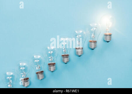 Blick von oben auf die Lampen in Reihe und einer von ihnen glühende auf blauem Hintergrund, die neue Idee Konzept Stockfoto