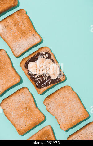 Blick von oben auf die Toasts mit Schokoladencreme und Banane auf blaue Fläche Stockfoto