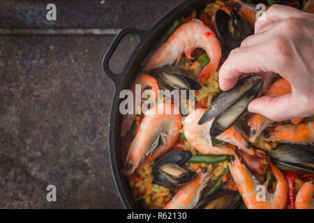 Hinzufügen von Muscheln auf der Pfanne mit Paella kochen, Ansicht von oben Stockfoto