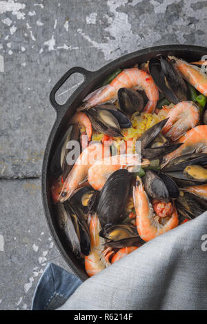 Paella in der Pfanne auf dem Metall Hintergrund vertikal Stockfoto