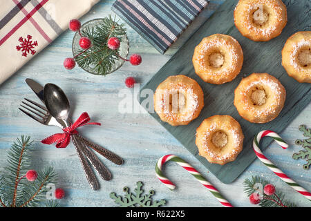 Mini bundt ring Kuchen mit Puderzucker auf hellen Hintergrund mit fir Zweige, Beeren und Zuckerstangen. Weihnachten süße Speisen. Stockfoto