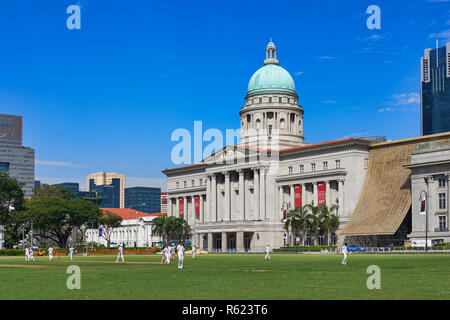 Blick vom Padang in Singapur auf die National Gallery Singapore (der ehemalige Oberste Gerichtshof), ein Cricket-Spiel, das auf dem Padang gespielt wird Stockfoto