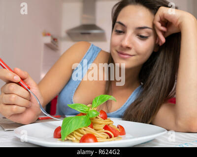 Junge Frau essen Vollkorn Spaghetti mit Tomaten und Basilikum Stockfoto