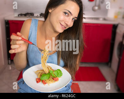 Junge Frau essen Vollkorn Spaghetti mit Tomaten und Basilikum Stockfoto