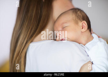Liebevolle Mutter kuscheln Schlafen Neugeborene Sohn über die Schulter