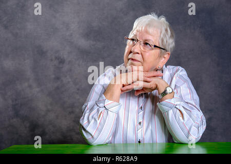 Grau behaarte ältere Frau auf der Suche entspannt Stockfoto