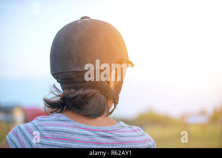 Porträt einer Frau, die ein Pferd reiten, Ansicht von hinten. Stockfoto