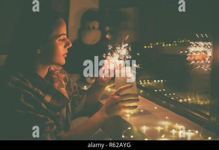 Junge Frau, die Lichter Feuerwerk zu Hause Stockfoto