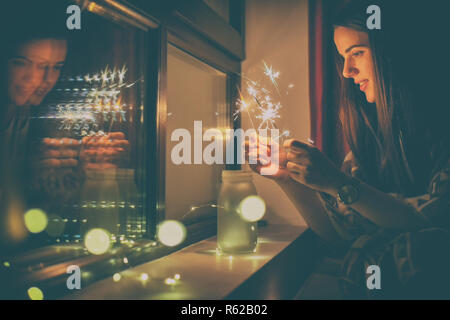 Junge Frau, die Lichter Feuerwerk zu Hause Stockfoto