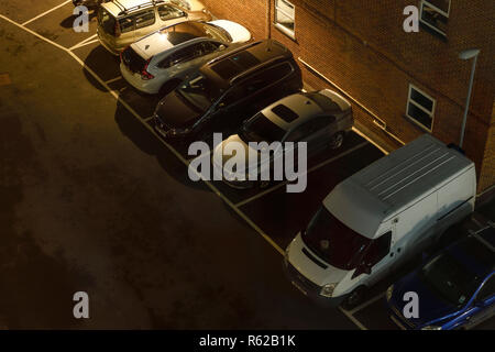 Fahrzeuge, die in einer schlecht beleuchteten open air Parkplatz geparkt in London, Großbritannien Stockfoto
