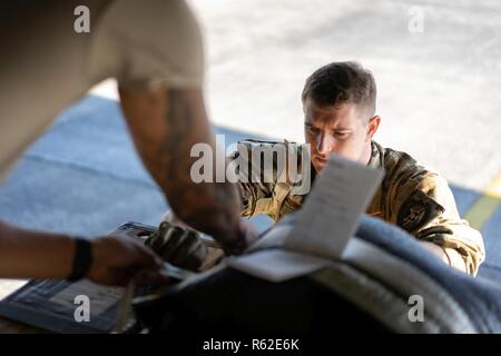 Staff Sgt. Christopher Hofer, 36th Airlift Squadron Lademeister, demonstriert die Takelage ein ow-Kosten, geringer Höhe Bündel in Vorbereitung für den Betrieb Weihnachten Tropfen an Yokota Air Base, Japan May, 16, 2018. OCD ist ein Training Mission, das hilft, die 374 Airlift Wing zusammen mit Partnern, die Koku Jieitai und der Royal Australian Air Force, aufrecht zu erhalten und die Bekämpfung der Bereitschaft durch nachhaltige Flugzeuge Erzeugung und Verwertung zu entwickeln. Stockfoto