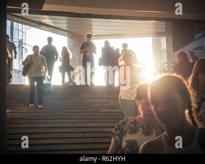 Moskau, Russland - September 6, 2018: Gewöhnliche Leute gehen, und gehen Sie auf die U-Bahn zur Hauptverkehrszeit. Menschen hinunter in die Unterführung. Silhouetten von Menschen zu Fuß auf der Treppe vor dem Hintergrund der Sonne. Stockfoto