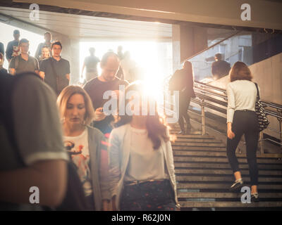 Moskau, Russland - September 6, 2018: Gewöhnliche Leute gehen, und gehen Sie auf die U-Bahn zur Hauptverkehrszeit. Menschen hinunter in die Unterführung. Silhouetten von Menschen zu Fuß auf der Treppe vor dem Hintergrund der Sonne. Stockfoto