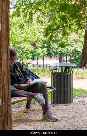 Bremen, Deutschland - 12. Juni 2011: Mann auf der Bank sitzen und lesen Zeitung auf die frische Luft draußen im gemütlichen Wallanlagen Park in Bremen, Deutschland Stockfoto