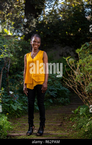 Ältere afrikanische Frau, stehend auf einem Gartenweg Stockfoto