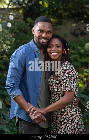 Ein Afrikanisches Paar einander umarmen in einem Garten Stockfoto