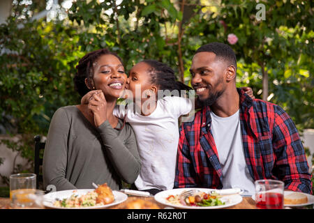 Eine Familie zusammen essen, Tochter Mutter Küssen auf die Wange Stockfoto