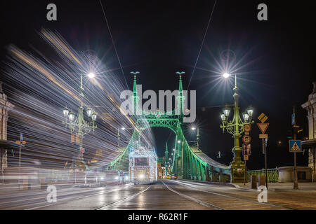 Budapest, Ungarn - festlich geschmückten Licht Straßenbahn (Fenyvillamos) unterwegs an der Freiheitsbrücke (szabadság Hid) in der Nacht. Weihnachten in Budapest Stockfoto