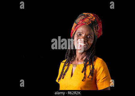 Eine ältere afrikanische Frau mit Kopftuch vor einem schwarzen Hintergrund Stockfoto
