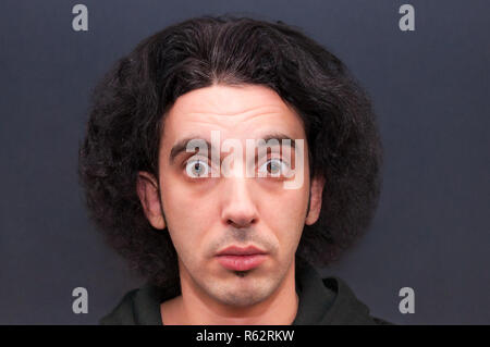 Schockiert, verwirrte Junge Mann mit großen geöffneten Augen und flauschige Frisur Stockfoto