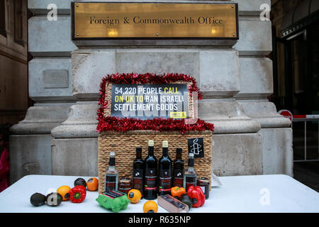 London, Großbritannien. 3. Dezember, 2018. Aktivisten von Amnesty International ein Weihnachten der "Israelische gestohlene Waren "einschließlich roter Wein, Olivenöl, Honig, Mineralwasser, Eier, Termine, Paprika, Orangen und Avocados für das Auswärtige Amt die Aufmerksamkeit auf die Tatsache, dass diese Ware derzeit alle in Israels illegale Siedlungen in den besetzten palästinensischen Westjordanland produziert wird und auf die Regierungen rund um die Welt, um die Einfuhr von Israelische Siedlung waren zu verbieten, behindern. Credit: Mark Kerrison/Alamy leben Nachrichten Stockfoto