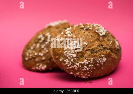Appetitliche Brötchen für Sandwich mit Kreuzkümmel und Salz auf einem rosa Hintergrund Stockfoto