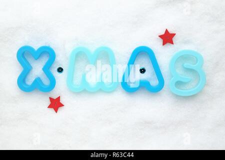 Weihnachten Konzept mit blauen Buchstaben, rote Sterne und weiss verschneiten Hintergrund. Festliche Hintergrund mit x-mas Dekoration. Draufsicht Perspektive und Copyspace Stockfoto