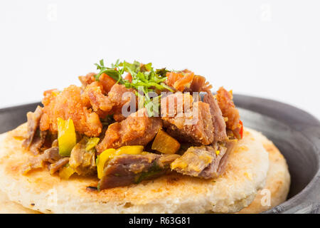 Kolumbianische arepa gekrönt mit zerkleinertem Rind- und Schweinefleisch Schwarte Stockfoto