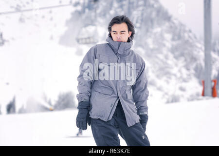 Asiatischer Mann snowboarden auf den verschneiten Berg Stockfoto