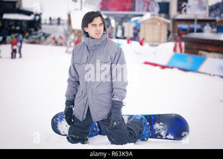 Asiatischer Mann snowboarden auf den verschneiten Berg Stockfoto