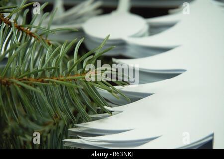 Vorbereitung umweltfreundliche Weihnachtsschmuck Konzept. Nahaufnahme der Stapel weißes Papier, Ornament und Zweig der Grünen Nadelholz Kiefer Stockfoto