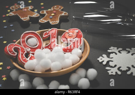 Weihnachtskarte: auf einer Holzplatte Es gibt rote Ingwer Cookies in der Form von Zahlen 2019 und Weiße runde Schneeflocken, neben dem Lügen Lebkuchen Stockfoto