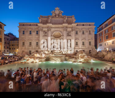 Massen von Touristen versammeln sich um das beleuchtete Trevi-Brunnen bei Einbruch der Dämmerung während der Blauen Stunde in Rom, Italien, und halten das ikonische Barock-Denkmal fest Stockfoto