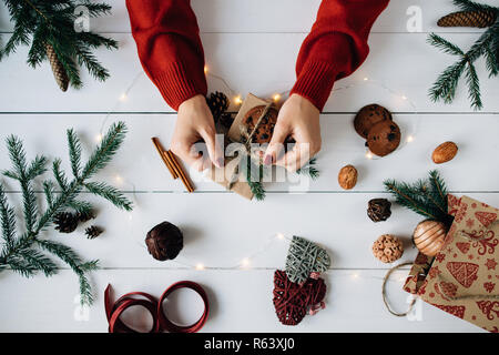 Der Frau die Hände bilden ein Weihnachtsgeschenk auf weissem Holztisch. Stockfoto