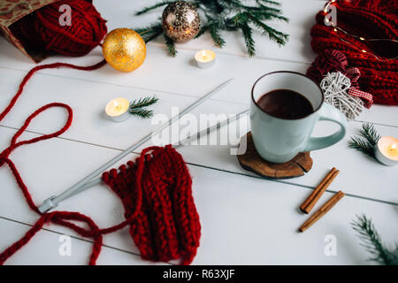 Stricknadeln, Kaffee und Kerzen, tanne Zweige und Weihnachtsbeleuchtung auf weißem Hintergrund. Stockfoto